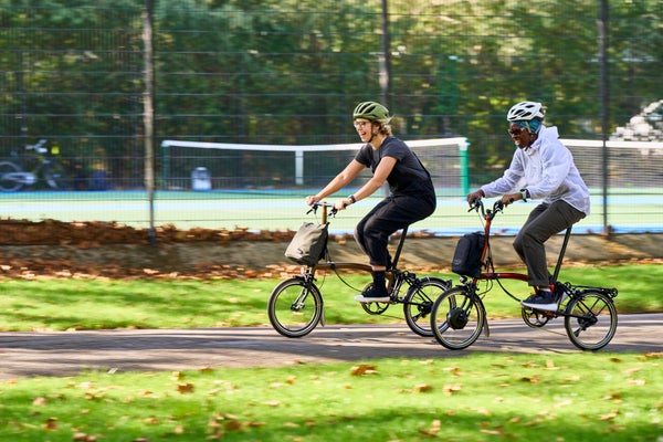 Deux femmes se promènent à vélo Brompton dans le parc.