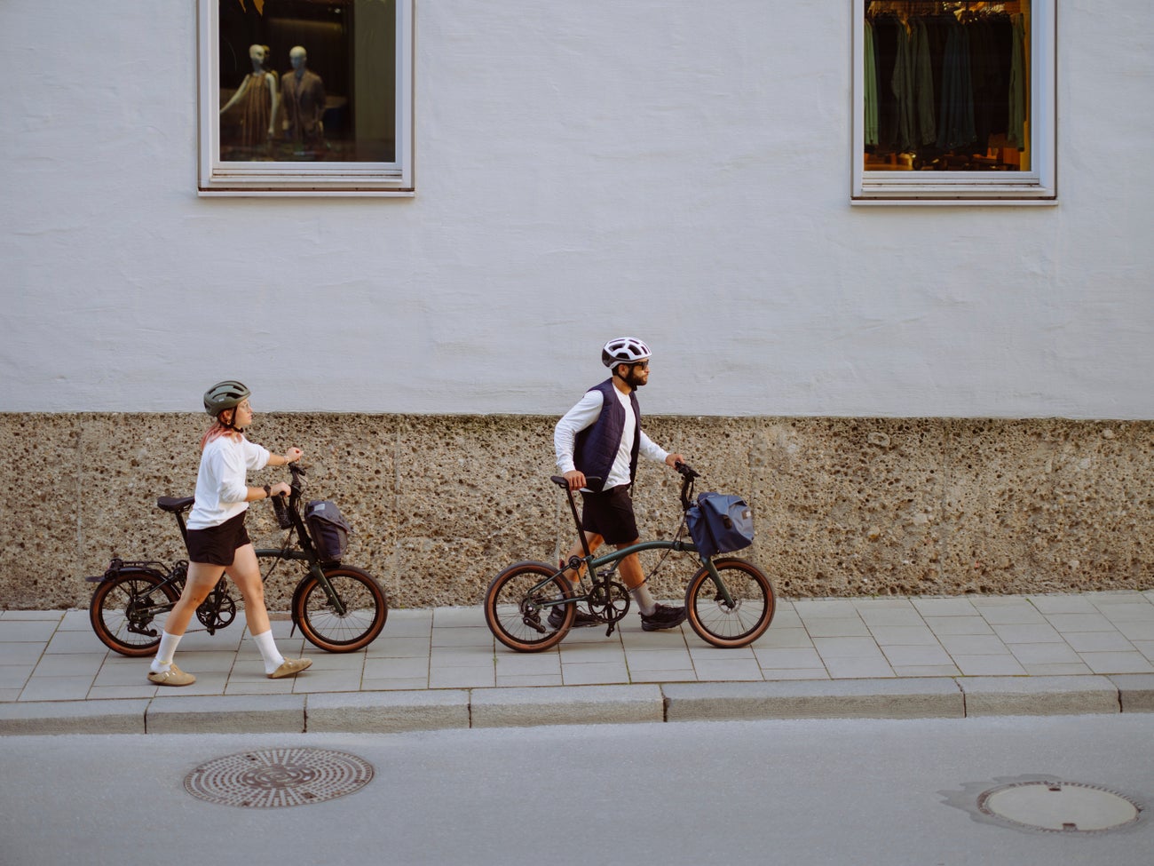 person rolling a folded brompton g line in front of orange backdrop
