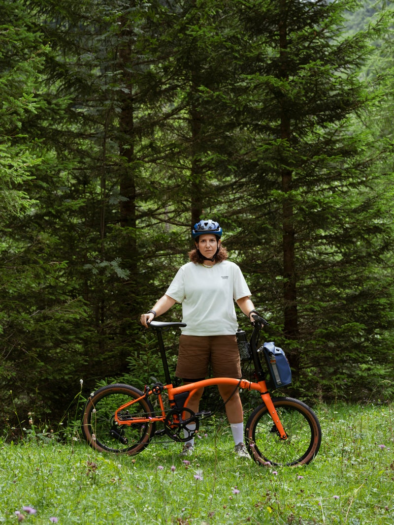person stood with a brompton g line bike in a forest