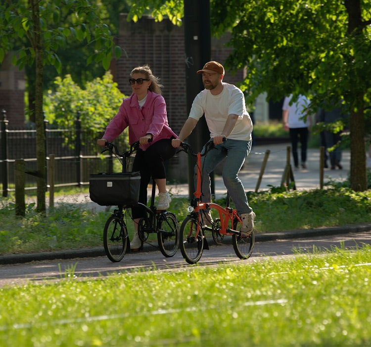 Deux personnes heureuses conduisant des vélos pliants Brompton dans une belle rue