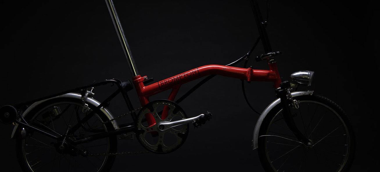 Un Brompton MK 1 rouge sous les projecteurs