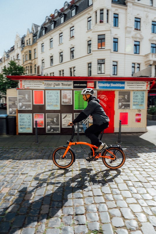 Personne roulant sur un vélo Brompton G Line dans une rue pavée