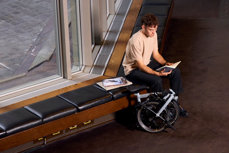 Brompton P Line lunar ice folded next to a seated person