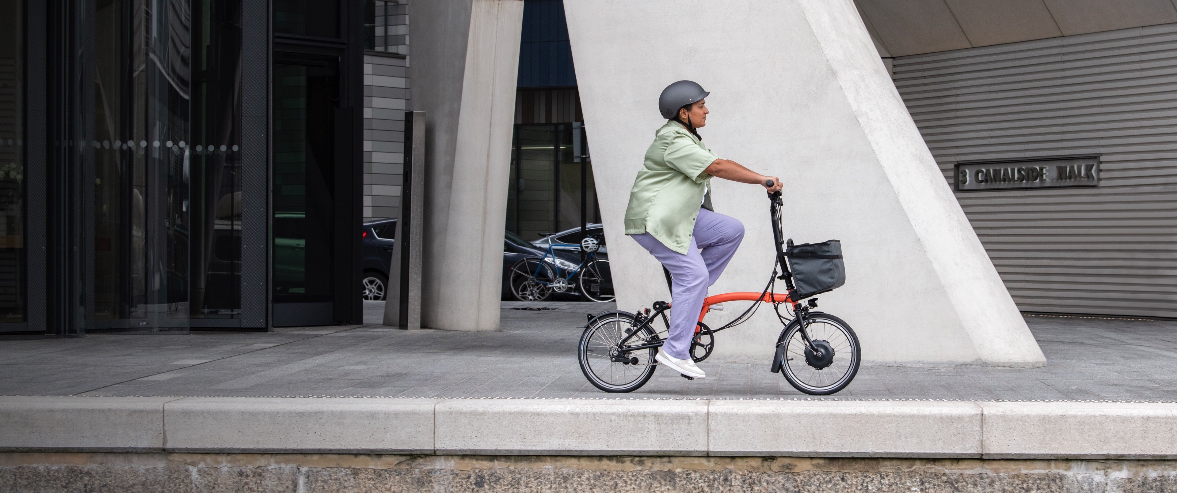 Une femme heureuse pédalant sur un Brompton Electric C Line à travers Central Park