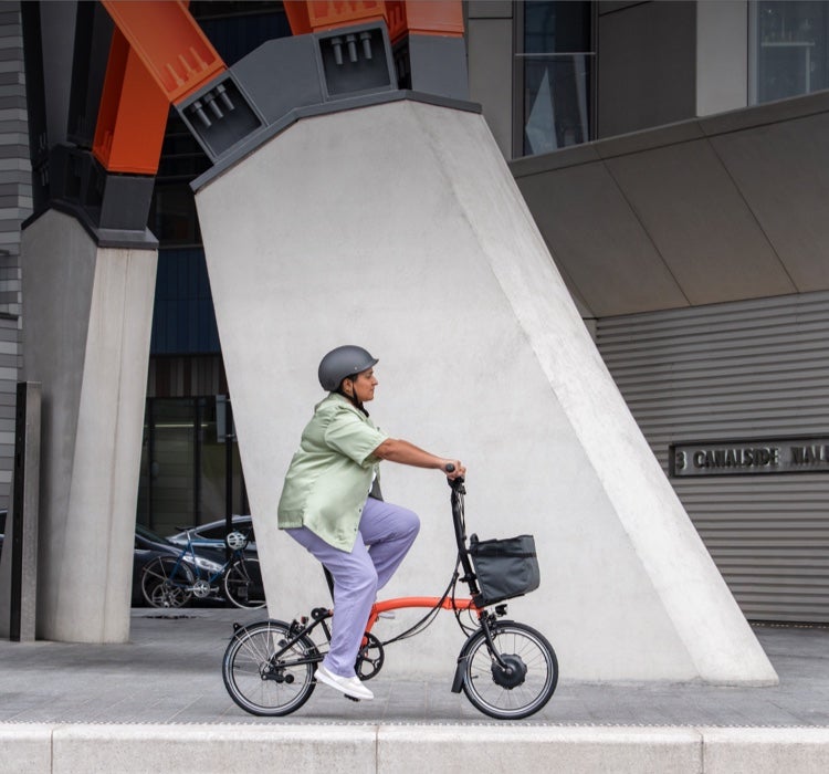 Une femme heureuse pédalant sur un Brompton Electric C Line à travers Central Park
