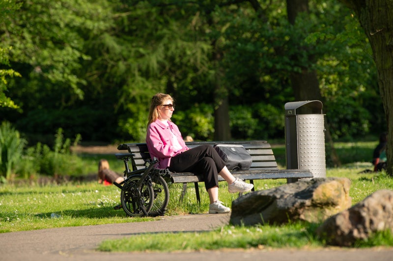 Personne assise sur un banc avec un vélo Brompton plié Deux personnes roulant sur des vélos Brompton
