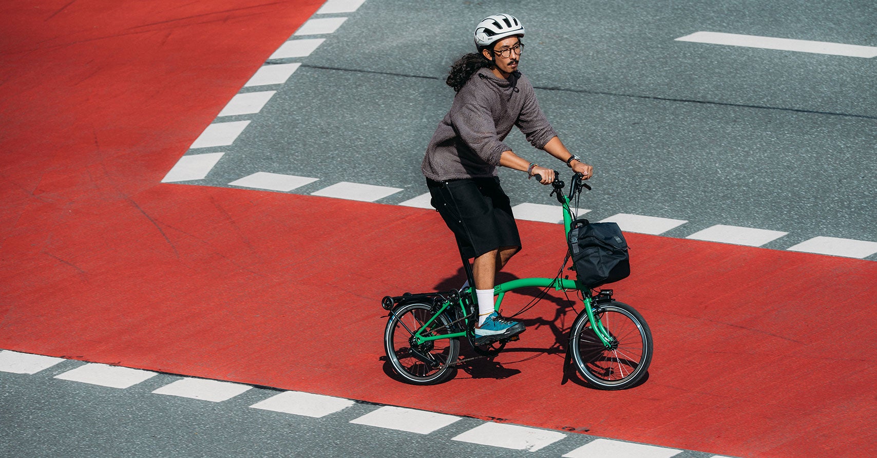 Un mec fait du vélo sur une piste cyclable goudronnée rouge.