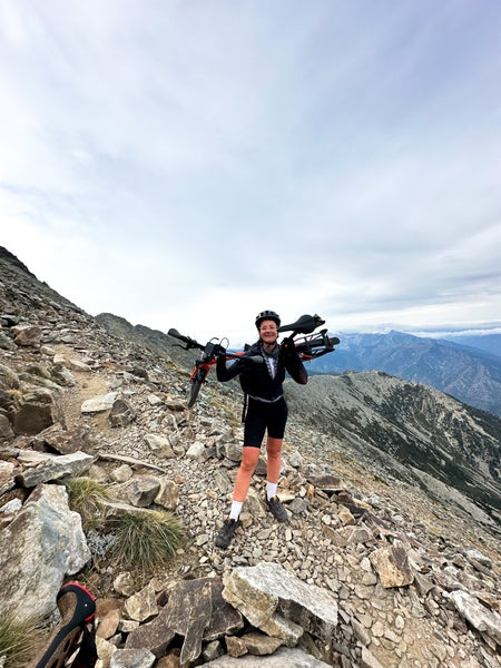 Sophie stood on a mountain with the Brompton G Line bike on her shoulders