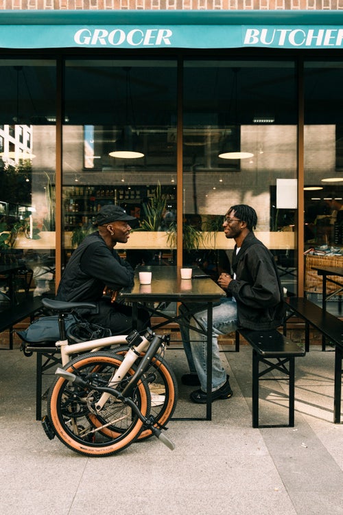 duke sat with friend and folded brompton g line bike