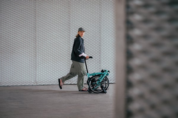 Femme poussant un vélo Brompton plié