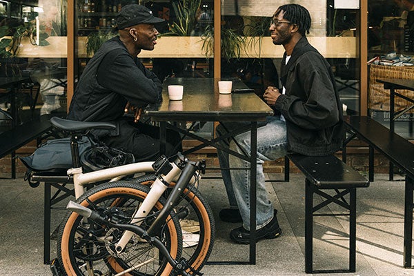 Deux personnes étaient assises devant un café avec des vélos Brompton G line pliés.