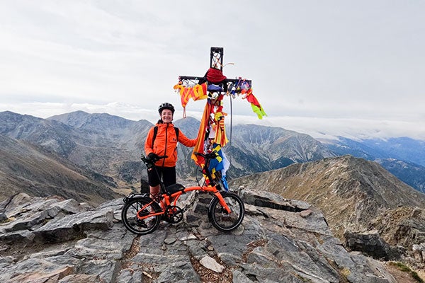 Une personne se tient au sommet d'une montagne avec un vélo Brompton G Line.