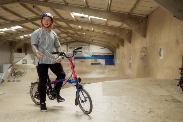 Une personne assise sur un vélo Brompton dans un skatepark