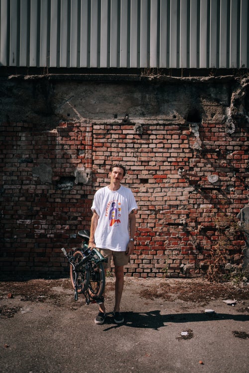 person stood carrying a folded brompton g line bike