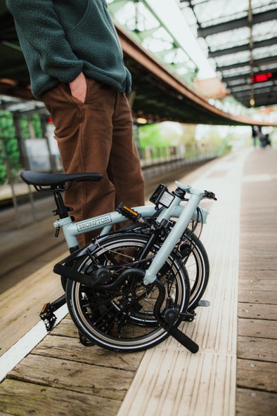 A man sitting on stairs with a folded Brompton P Line bike