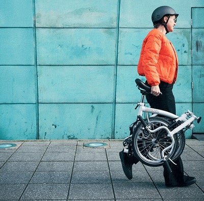 person carrying a folded brompton a line bike