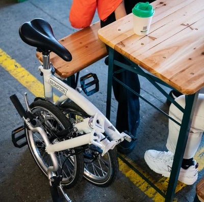brompton a line bike folded by a table