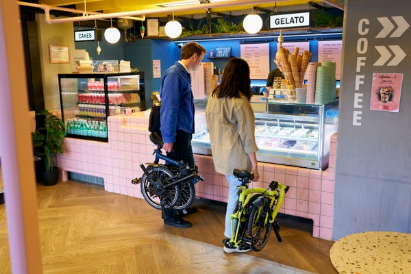 Deux personnes au comptoir de glaces tenant leurs vélos pliés Brompton C Line